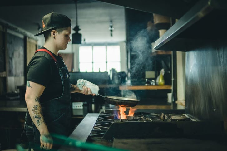 chef cooking over a gas stove, smoke rising from pan